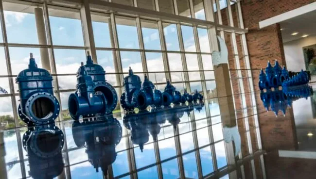 avk-kontainer-artikel-768x417 AVK - A group of blue water pipes in front of a large window.